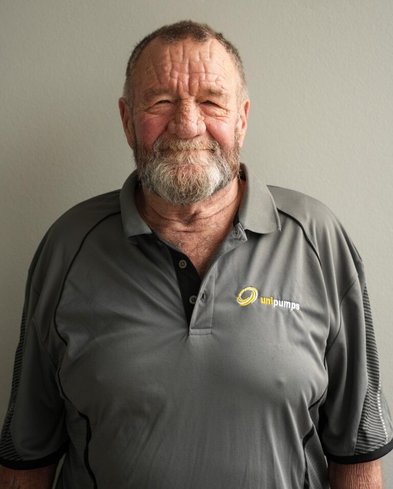 Rodney Thwaites, older man with beard and mustache, in gray unipumps polo shirt against plain wall.